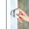 A hand is shown holding a white suction cup handle attached to a glass surface. Produktbild-Vorschau