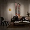 A couple relaxing on a couch in a living room, with a pendant light hanging above. Produktbild-Vorschau