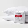 Two white quilted pillow protectors are stacked, with a packaged set of pillow protectors in the foreground. Anteprima dell’immagine prodotto