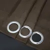A close-up view of three silver grommets on a brown curtain. Produktbild-Vorschau