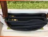 A close-up view of a dark blue handbag with multiple zippered compartments and a brown strap. Produktbild-Vorschau