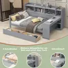 A grey daybed with storage drawers, a desk attachment, and shelving, shown in a room setting with pillows and blankets. Produktbild-Vorschau