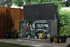 A garden shed filled with gardening tools and a bicycle, set in a backyard with a wooden fence and plants. Náhľad obrázku produktu
