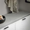 A close-up view of a bench with a cushion and a blanket draped over it, next to a black bowl filled with bread. Anteprima dell’immagine prodotto