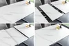 A collage of four images showing a white ceramic marble-effect extendable dining table with a black metal base, viewed from different angles and at different extension stages. Produktbild-Vorschau