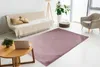 A living room scene with a sofa, armchair, coffee table, and a rug. Produktbild-Vorschau