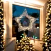 A lit star decoration hangs in a window with Christmas trees in the background. Anteprima dell’immagine prodotto