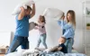 A family is having a pillow fight on a bed. Produktbild-Vorschau