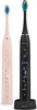 Two electric toothbrushes, one pink and one black, are displayed side-by-side against a white background. The black toothbrush is placed on a charging base. Náhled obrázku produktu