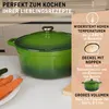 A green enameled cast iron Dutch oven is shown on a kitchen counter with carrots and a cucumber nearby. Text overlays describe its features. Produktbild-Vorschau
