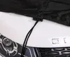 A close-up view of a black car cover with a drawstring and toggle, placed on the hood of a white car. Produktbild-Vorschau