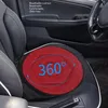 A red, round car seat cushion with a hexagonal pattern and blue text indicating "360°" is placed on a black car seat. The image also shows parts of the car's interior, including the door panel and steering wheel. Náhled obrázku produktu