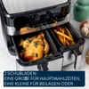 A close-up of a dual-chamber air fryer with food inside, with text overlay describing its features. Produktbild-Vorschau
