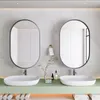 A modern bathroom with two oval mirrors above two sinks, a green vanity, and towels. Produktbild-Vorschau
