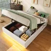 A bed with storage is open, revealing folded blankets and pillows inside. The bed is made with green and white bedding, and there are two glowing green symbols on the pillows. Voir les images du produit