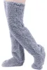 Paar graue flauschige Overknee-Socken an Beinen, auf weißem Hintergrund stehend Náhled obrázku produktu