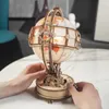 Hands interacting with a wooden globe lamp on a table. Náhľad obrázku produktu
