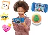 A young girl is holding a blue VTech Kidizoom Touch 5.0 camera, with various emojis and a dinosaur animation displayed around her. The camera is shown in use, with a screen displaying a pink character. Podgląd zdjęcia produktu