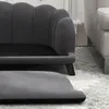 A close-up view of a dark gray dog couch with a scalloped backrest and a separate footrest in the foreground. Náhled obrázku produktu