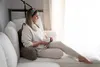 A woman is sitting on a couch, holding a mug, and looking out a window. Náhled obrázku produktu