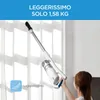A woman is holding a cordless vacuum cleaner in front of a window with sheer curtains. Produktbild-Vorschau