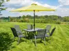 A patio table and chairs set with a large umbrella, set up on a grassy lawn. Produktbild-Vorschau