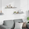 Two gray shelves mounted on a white wall above a gray sofa with pillows. Podgląd zdjęcia produktu