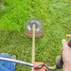 A person is using a string trimmer to cut grass. Podgląd zdjęcia produktu