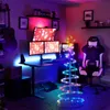A gaming setup with a desk, multiple monitors, a gaming chair, and a decorative LED spiral Christmas tree. Náhľad obrázku produktu