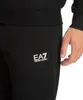 A close-up shot of a person wearing black sweatpants with the EA7 logo on the left thigh. Produktbild-Vorschau