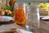 A kitchen counter with jars of preserved fruit, lemons, and a wooden spoon. Anteprima dell’immagine prodotto