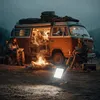 People camping around a campfire next to a camper van at dusk. Anteprima dell’immagine prodotto