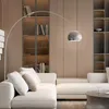 A modern living room with a sectional sofa, a floor lamp, and built-in bookshelves. Anteprima dell’immagine prodotto