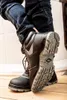 A person wearing dark blue jeans and black work boots, with the sole of one boot prominently displayed. Náhľad obrázku produktu