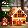 A wooden advent calendar shaped like a gingerbread house, set against a blurred Christmas tree background. Produktbild-Vorschau