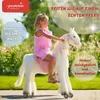 A young girl riding a white toy horse in an outdoor setting. Anteprima dell’immagine prodotto