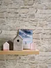 A shelf with decorative items against a stone-patterned wallpaper. Produktbild-Vorschau