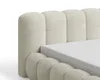 A close-up view of a beige upholstered bed frame with a white mattress. Voir les images du produit