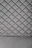 A close-up view of a quilted gray headboard with a plain gray base. Produktbild-Vorschau