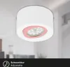 A white LED ceiling light with a pink accent ring and visible LED bulbs, mounted on a white ceiling. The background is blurred, showing a hint of an interior room. Náhľad obrázku produktu
