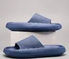 Zwei blaue Slidesandalen, eine auf einem weißen Block und eine auf dem Boden, mit strukturierter Sohle und geripptem Riemen Anteprima dell’immagine prodotto