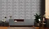 A modern living room with a gray media console against a stone-patterned wall, featuring a plant and a small table. Produktbild-Vorschau