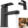 A black faucet with water running, and a woman washing her hands in a sink. Produktbild-Vorschau