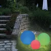 Three illuminated solar spheres in blue, green, and red are placed on a grassy lawn next to a stone staircase and wall in a garden setting at dusk. Produktbild-Vorschau