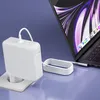 A white laptop charger is plugged into a wall outlet and connected to a laptop. Podgląd zdjęcia produktu