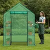 A woman waters plants inside a green greenhouse. Voir les images du produit