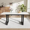 A white dining table with black legs is set up in a well-lit room with a light rug and wooden furniture in the background. Produktbild-Vorschau