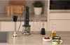 A kitchen counter with a hand blender and its accessories, along with ingredients like basil, sun-dried tomatoes, and nuts. Anteprima dell’immagine prodotto