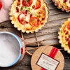 A close-up shot of small quiches on a cooling rack, with a salt container and a cork coaster with text on it. Voir les images du produit