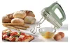 A mint green retro-style hand mixer is displayed with various baked goods and ingredients, including bread, rolls, breadsticks, pizza, eggs, and a bowl of eggs. Voir les images du produit
